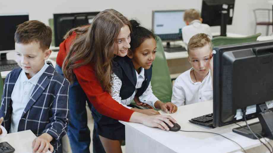 Teacher helping pupils on computers